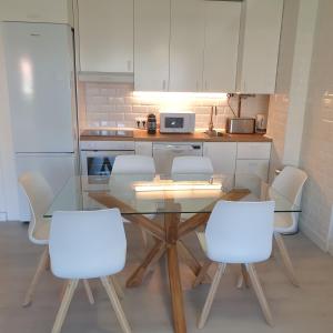 cocina con mesa de cristal y sillas blancas en Sea View Apartment Beach Front Punta Prima, en Torrevieja