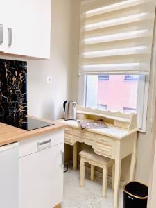 eine weiße Küche mit einem Schreibtisch und einem Fenster in der Unterkunft De-Luxe-Apartment im Zentrum in Ravensburg