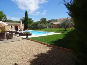 un patio trasero con piscina y una casa en Mas'Xime en Saint-Rémy-de-Provence