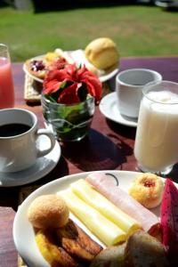 una mesa con platos de comida y una taza de leche en Pousada Natureza Viva, en Itacaré