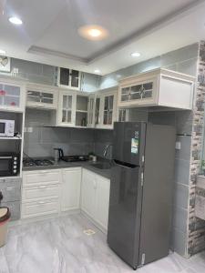 La cuisine est équipée de placards blancs et d'un réfrigérateur noir. dans l'établissement استراحة زهرة الاماكن 2, à Djeddah