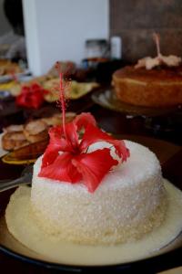 a white cake with a red flower on a table at Pousada Natureza Viva in Itacaré