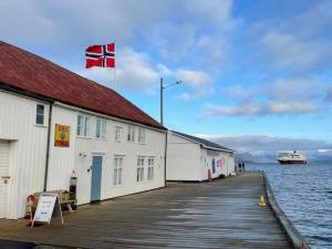 a building on a dock with a flag on it at 1. etg i Dampskipsbrygga, Lødingen havn in Lødingen