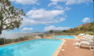 a swimming pool with white chairs and a fence at Terrasse du Levant in Bocca del Oro