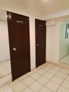 - deux portes noires dans une chambre revêtue de carrelage blanc dans l'établissement Estancia la Ocho, à Tijuana