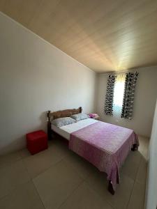 een slaapkamer met een bed met een paarse deken en een raam bij Casa Rosemary in Lauro de Freitas