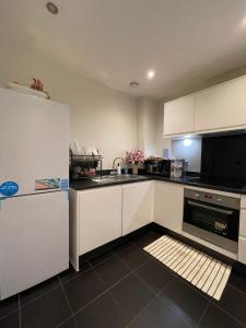 a kitchen with white cabinets and a sink and a refrigerator at Peaceful shared flat 30mins Central London in Colindale