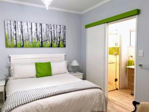 a bedroom with a bed with a green painting on the wall at Greenwood Cottage, Somerset West in Somerset West