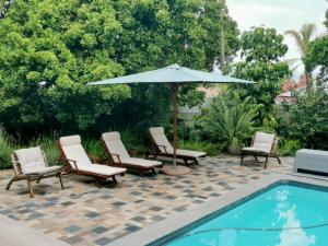 a group of chairs and an umbrella next to a pool at Greenwood Cottage, Somerset West in Somerset West