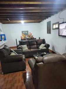 a living room with leather couches and a television at Casa Rincón Ojojona in Media Legua