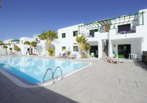 a swimming pool in front of a white building at Apartamentos Aloe in Puerto del Carmen