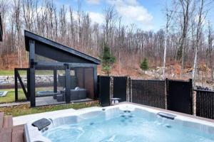 a jacuzzi tub in a yard next to a fence at Château Céleste - Villa with pool, hot tub, fire pit in Cantley