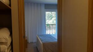 a bedroom with a bed and a window with a balcony at Golden Laghetto Gamado in Gramado