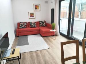 czerwona kanapa w salonie z oknem w obiekcie Cosy Home near Central London E1 w Londynie