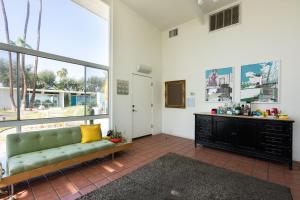 uma sala de estar com um sofá verde e uma janela em The Monkey Tree Hotel Buyout by AvantStay Entire Hotel Buyout Funky Rooms w Modern Amenities em Palm Springs
