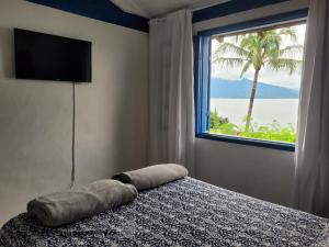 um quarto com uma cama e uma janela com uma palmeira em ILHABELA Vista Panorâmica em Ilhabela