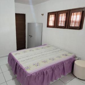 a bed in a room with a purple bedspread at Casa em Tibau RN in Tibau