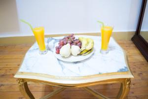 un plato de fruta en una mesa con dos vasos de zumo de naranja en golden palace down town, en El Cairo