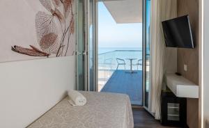 a room with a bed and a balcony with a television at Hotel Harmony in Rimini