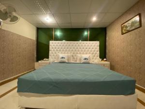 1 dormitorio con 1 cama grande y pared verde en Fusion Lodge, en Islamabad