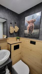 a bathroom with a picture of a cow on the wall at FeWo Gretel in Schönwald +19 photos