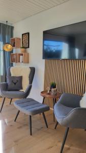 a living room with two chairs and a tv on the wall at FeWo Gretel in Schönwald