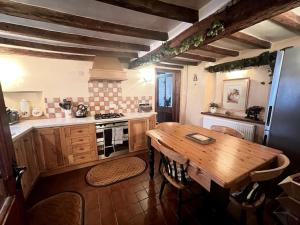 uma cozinha com uma mesa de madeira e um fogão em Grace Dieu Cottage - Sleeps 7 em Whitwick