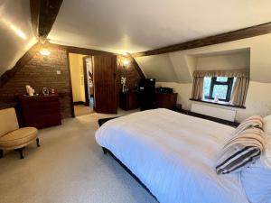Whitwick的住宿－Grace Dieu Cottage - Sleeps 7，卧室配有一张白色大床和一把椅子