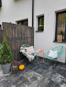 een patio met 2 stoelen, een tafel en een hek bij Pokoje przy Parkowej in Zwierzyniec