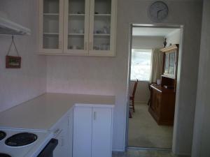uma cozinha com armários brancos e um relógio na parede em Warm & welcome on Whiteley em New Plymouth