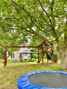 un parque infantil con una cama elástica y un árbol en Luca Apartman en Gyenesdiás