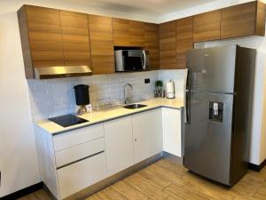 a kitchen with a stainless steel refrigerator and wooden cabinets at EÓN 9 - Moderno, vista volcán, aire acondicionado in Guatemala