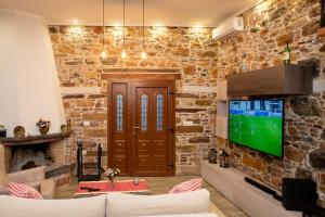 uma sala de estar com uma parede de pedra e uma televisão em ΠΕΤΡΙΝΟ ΣΠΙΤΙ ΣΤΟΝ ΚΑΜΠΟ ΧΙΟΥ em Quios