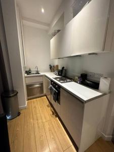 a kitchen with white cabinets and a wooden floor at Sleep 6 Piccadilly Grand in London VR5 in London