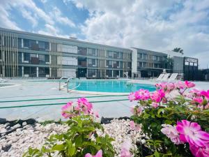 a building with a swimming pool and pink flowers at Bokai Garden Hotel in Rosemead