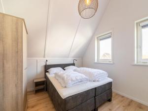 Un dormitorio con una cama con almohadas blancas. en Modern holiday home in Scherpenisse with garden, en Scherpenisse