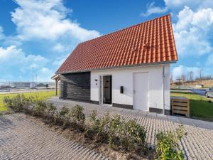 un pequeño edificio blanco con techo rojo en Modern holiday home in Scherpenisse with garden, en Scherpenisse