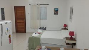 ein weißes Zimmer mit einem Bett und einem Telefon darauf in der Unterkunft Loft LISBOA para Casais, em Iguaba Grande, 3 Pessoas, 150 metros da praia in Iguaba Grande