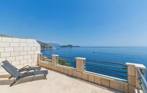 a chair sitting on a balcony overlooking the water at Big Blue Apartments in Dubrovnik