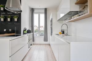 uma cozinha com armários brancos e piso de madeira em La Casa Blanca - 6 personnes proche Disney & Paris em Le Raincy