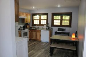 a kitchen with white appliances and a wooden table at Small House, 2 queen bedrooms, 1 bath, on route 33 in Nelsonville