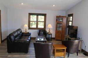 a living room with a leather couch and a tv at Small House, 2 queen bedrooms, 1 bath, on route 33 in Nelsonville