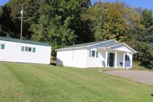 a white building with a grassy field in front of it at Small House, 2 queen bedrooms, 1 bath, on route 33 in Nelsonville