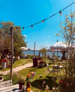 een tuin met tafels, stoelen en parasols bij NEW: Summerhouse near beach&lake in Noordwijkerhout