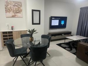 ein Esszimmer mit einem Glastisch und Stühlen sowie einem TV in der Unterkunft Fourways Oasis in Sandton
