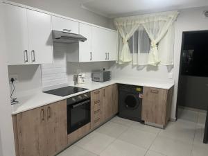 cocina con armarios blancos, lavadora y secadora en Fourways Oasis, en Sandton