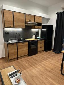 eine Küche mit Holzschränken und einem schwarzen Kühlschrank in der Unterkunft One Fine Stay in Piräus