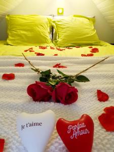 Una cama con rosas rojas en el suelo con corazón en Bienvenue dans le chartreuse 2 à 6 couchages, en Cholonge