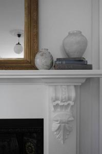 a shelf with vases and books on top of a fireplace at The Cobbler in Royal Park