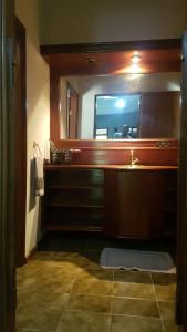 a bathroom with a sink and a large mirror at Quarto Quádruplo in São Pedro